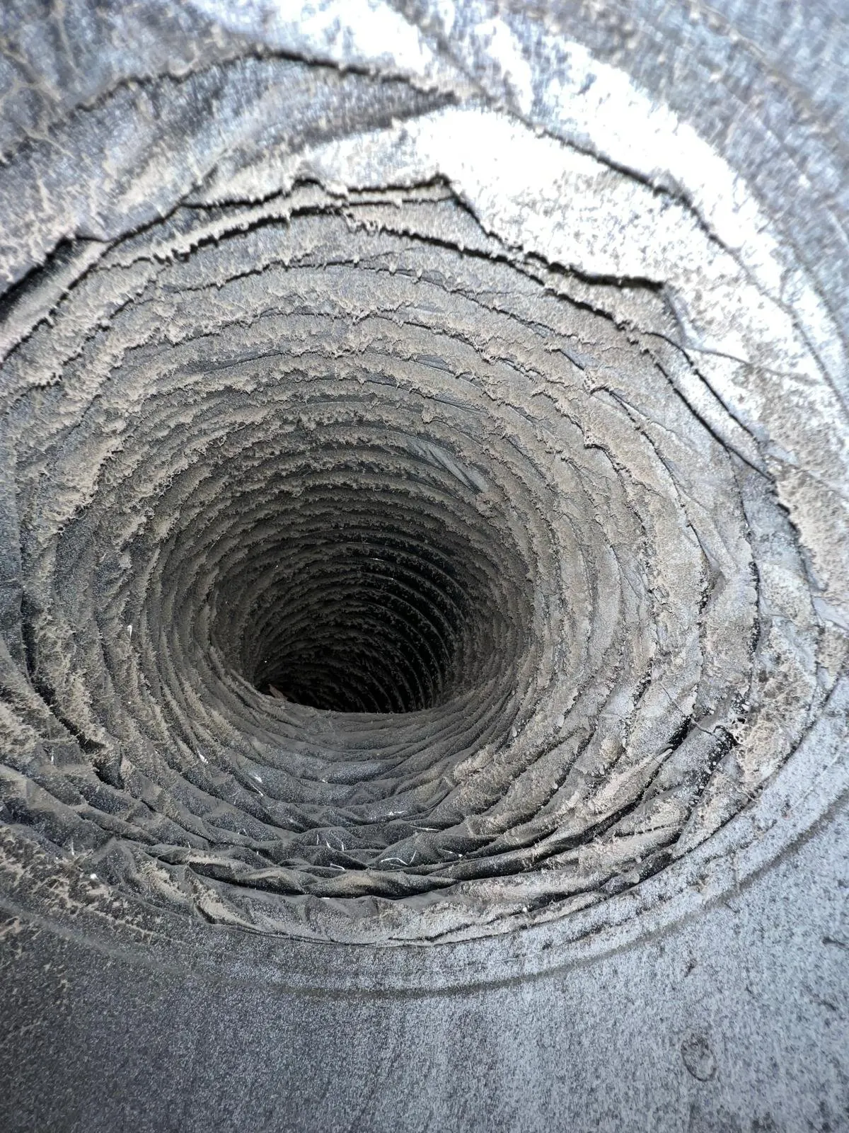 Inside of a flexible air duct heavily coated with dust and debris before cleaning